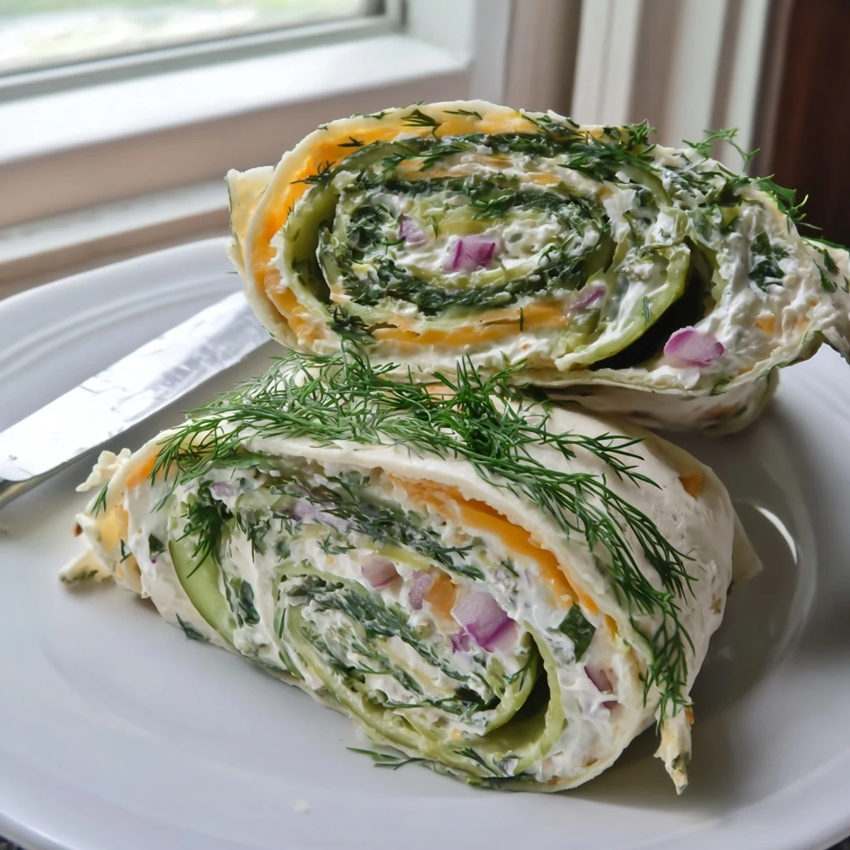 Colorful plate of pickle-in-a-blanket bites, drizzled with mustard, ideal for parties.  