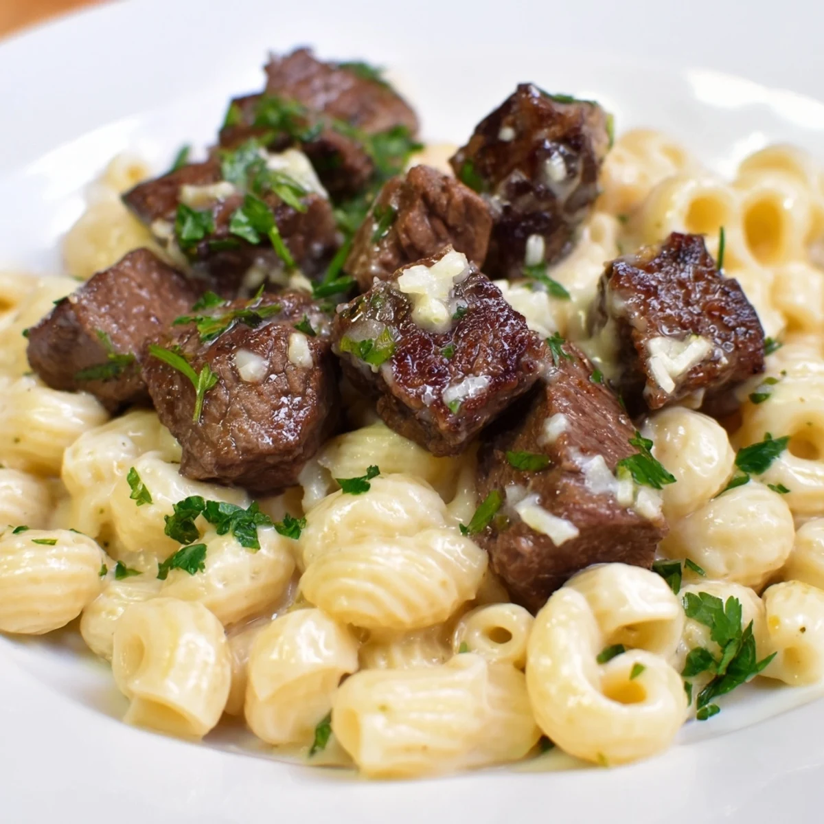 Sizzling garlic butter coats these tender Garlic Butter Steak Bites, served atop creamy cheddar shells.
