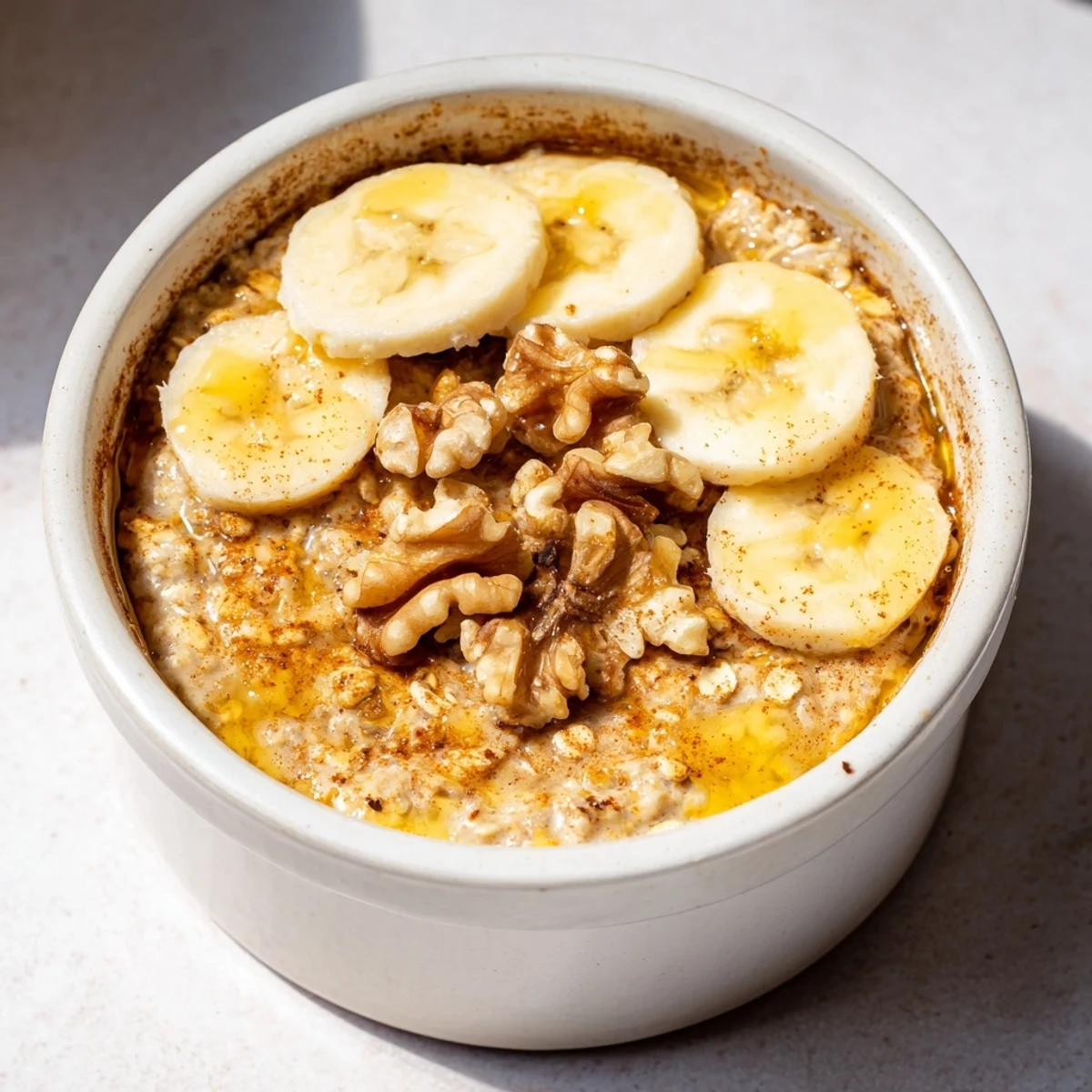 Golden-brown baked oats ramekins with sweet banana slices and a honey drizzle for breakfast.