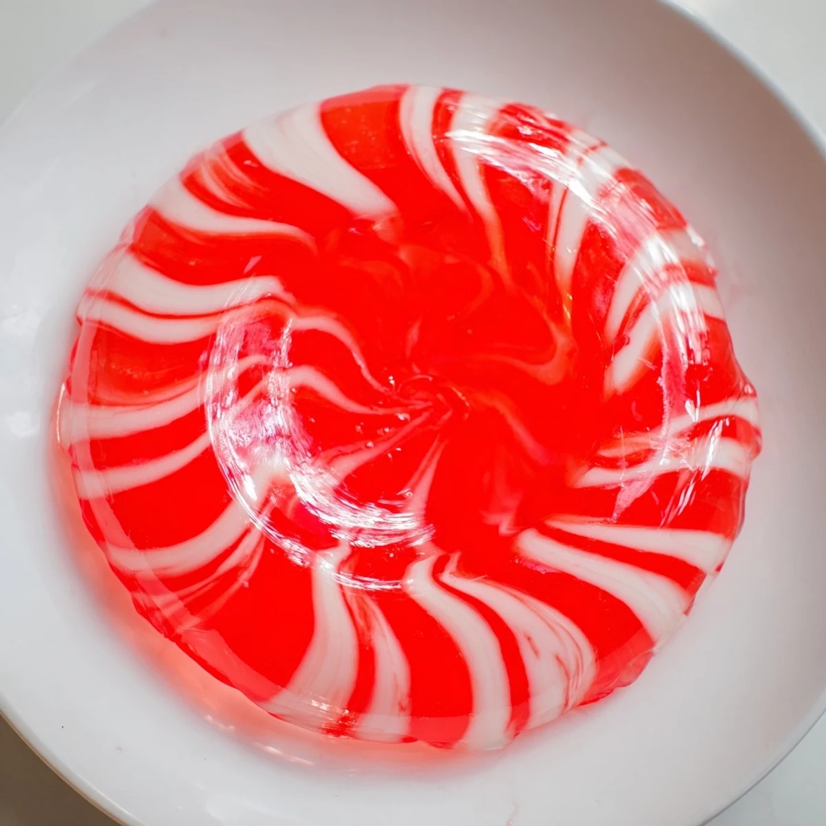 The warm, transparent glow of a melted no-bake peppermint candy bowl sits perfectly on a table.
