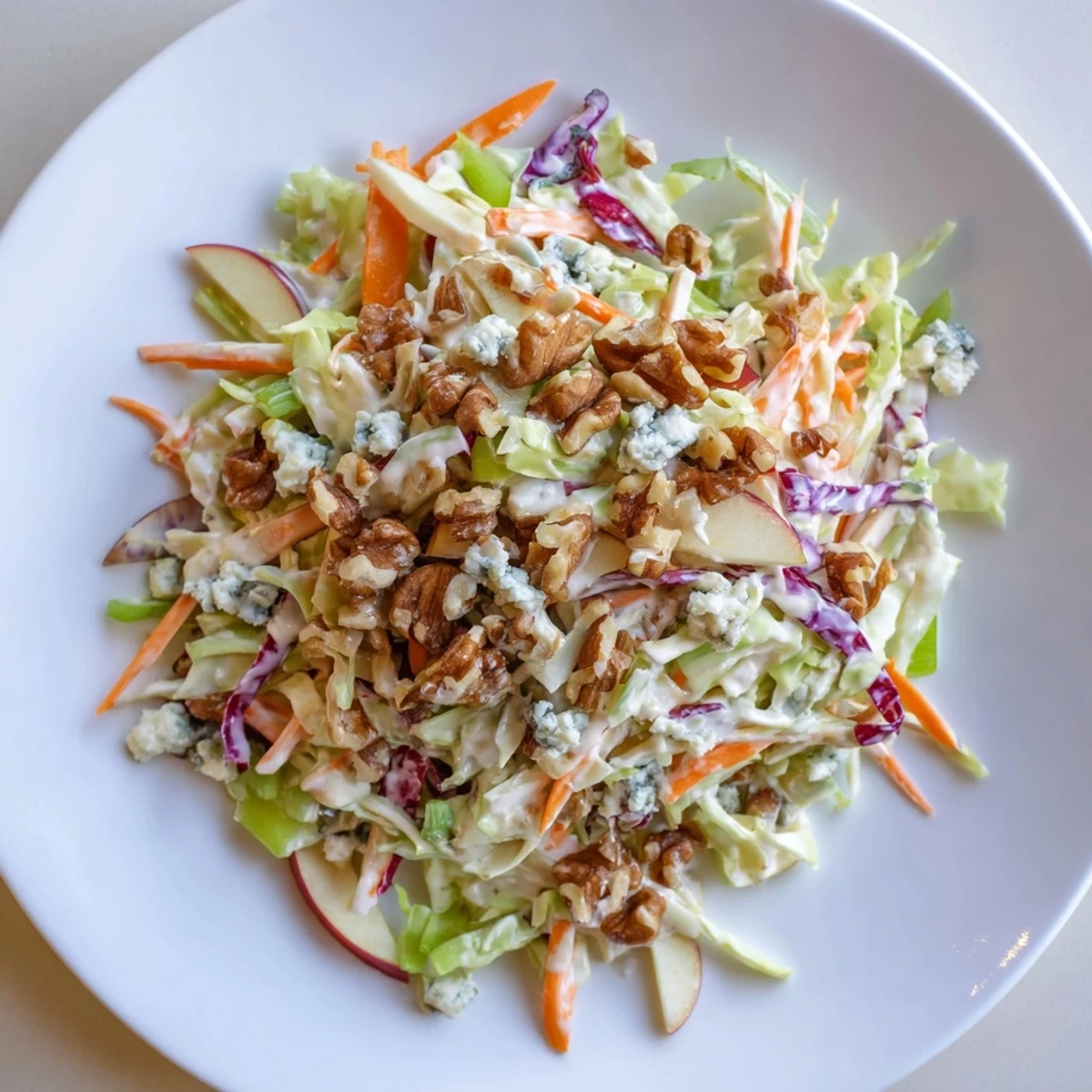 A bowlful of colorful Crunchy Apple & Walnut Slaw with Blue Cheese, topped with blue cheese crumbles.