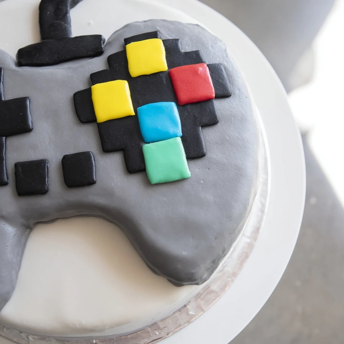 A vibrant, pixel video game controller cake with brightly colored buttons, ready to eat.
