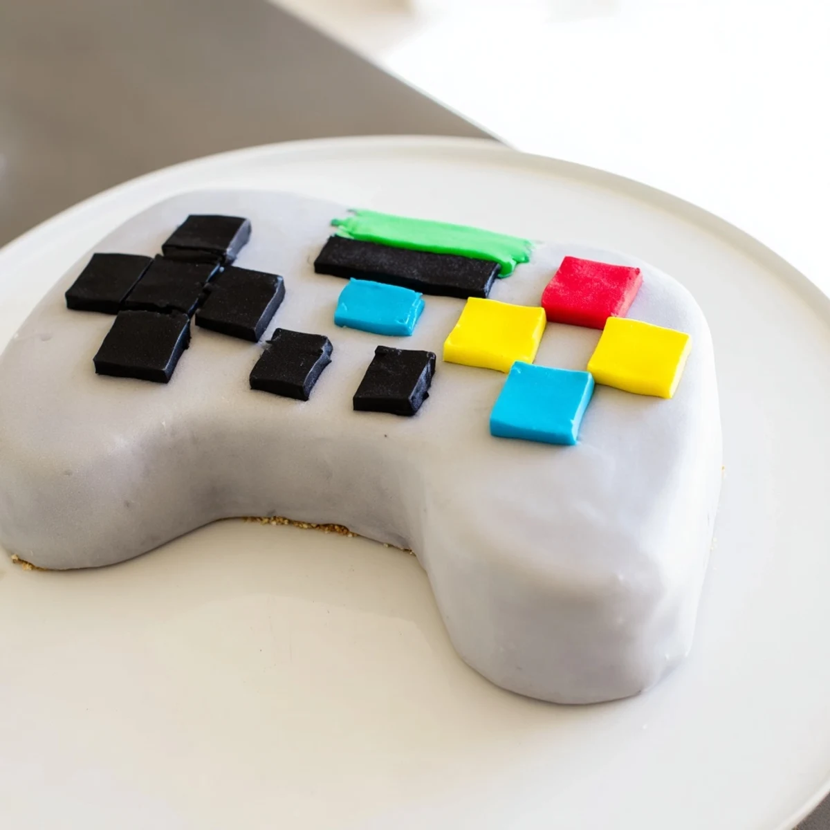 Delicious vanilla cake layers iced in fondant form a detailed pixel controller cake.