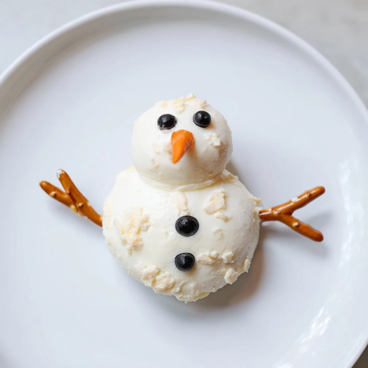 Close-up of adorable Melted Snowman Cheese Bites with olive eyes and carrot noses, perfect for parties.