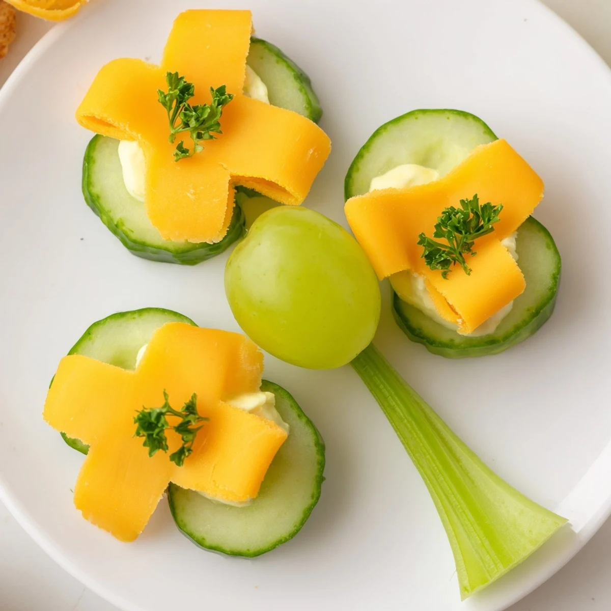 Vibrant Lucky Four-Leaf Clover Snack: Cucumber and cheddar cheese shamrocks arranged with green grape centers.