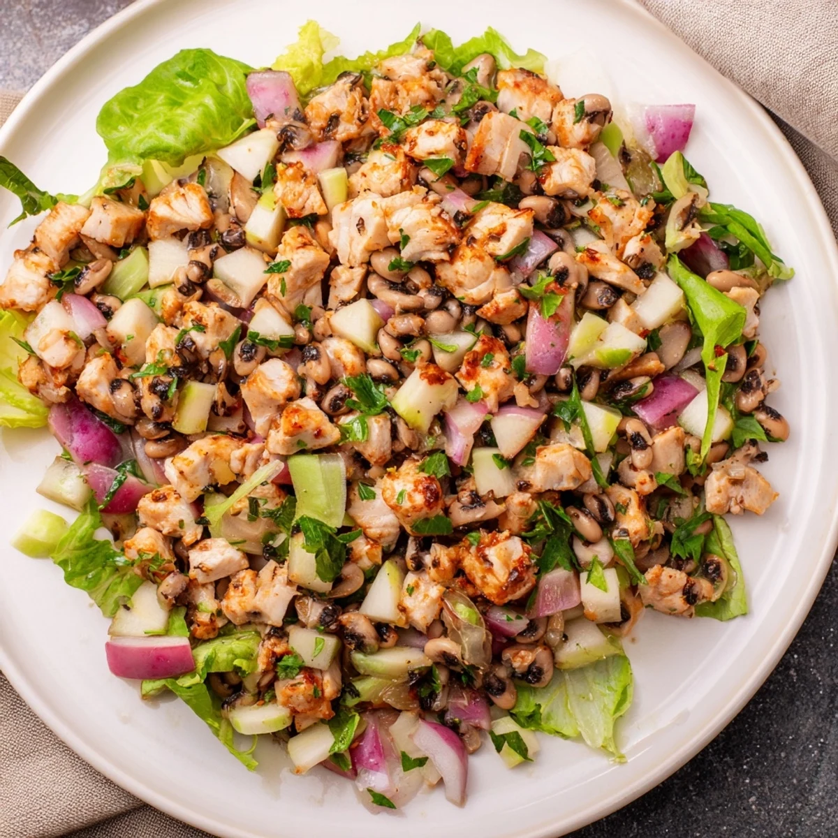 Chicken and Apple New Years Luck Salad, tossed in a tangy dressing, shows fresh ingredients ready to be served.