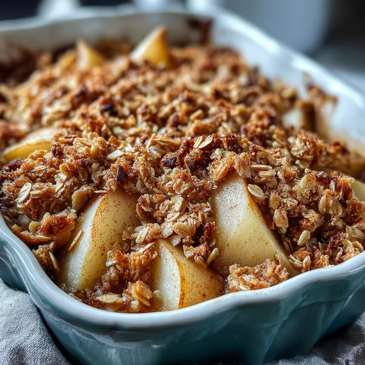 Golden baked Pear Crumble bubbling in a dish, topped with vanilla ice cream melting over the warm, crunchy crumble.