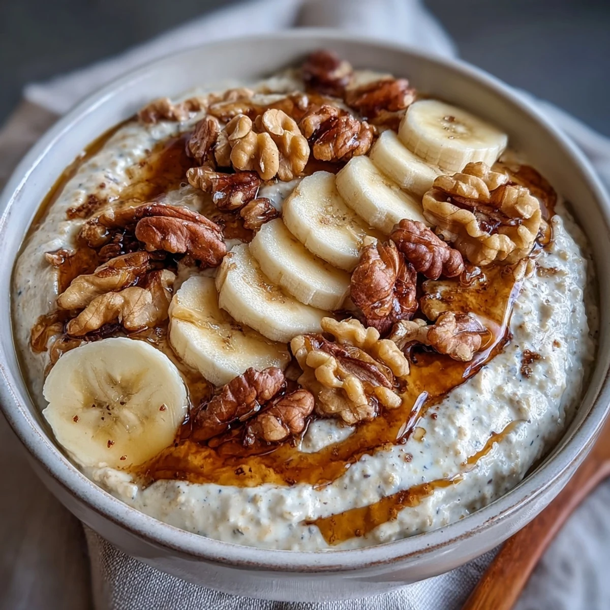 Creamy banana bread-inspired oats with Greek yogurt, maple syrup, and walnuts, served in a jar with sliced bananas on top.