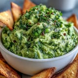 Vibrant green edamame guacamole with ripe avocado, perfect for dipping warm, spiced pita chips.  