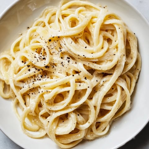 Creamy Lazy Girl Three-Ingredient Pasta glistening with melted butter and Parmesan cheese, ready to eat.