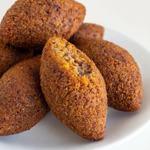 Golden-brown Lebanese Kibbeh, perfectly fried, ready to be enjoyed with a creamy yogurt dip.