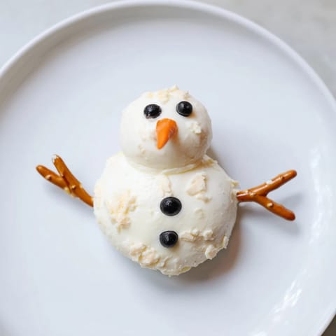 Close-up of adorable Melted Snowman Cheese Bites with olive eyes and carrot noses, perfect for parties.