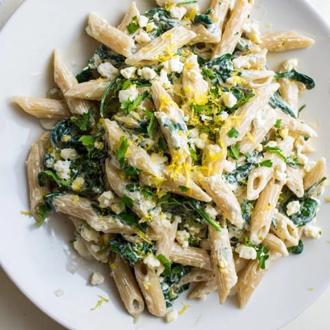 Savory Creamy Feta Spinach Pasta served in a white bowl, garnished with fresh basil and lemon zest for a bright finish.