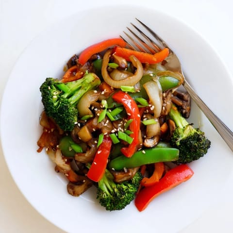 Tossing broccoli, carrots, and snap peas with aromatic ginger and garlic in a hot skillet for a quick, healthy vegan dinner.