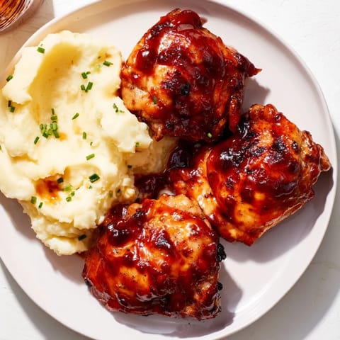Golden-brown honey BBQ chicken thighs, glistening with sauce, served with perfect garlic mashed potatoes.
