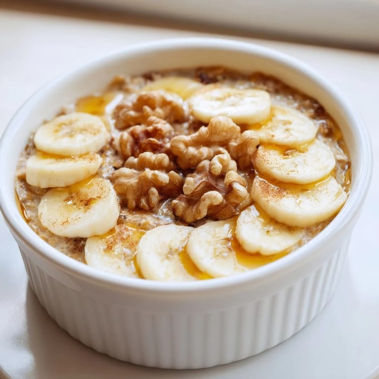 Individual baked oats ramekins are filled with creamy oats and banana, topped with walnuts.