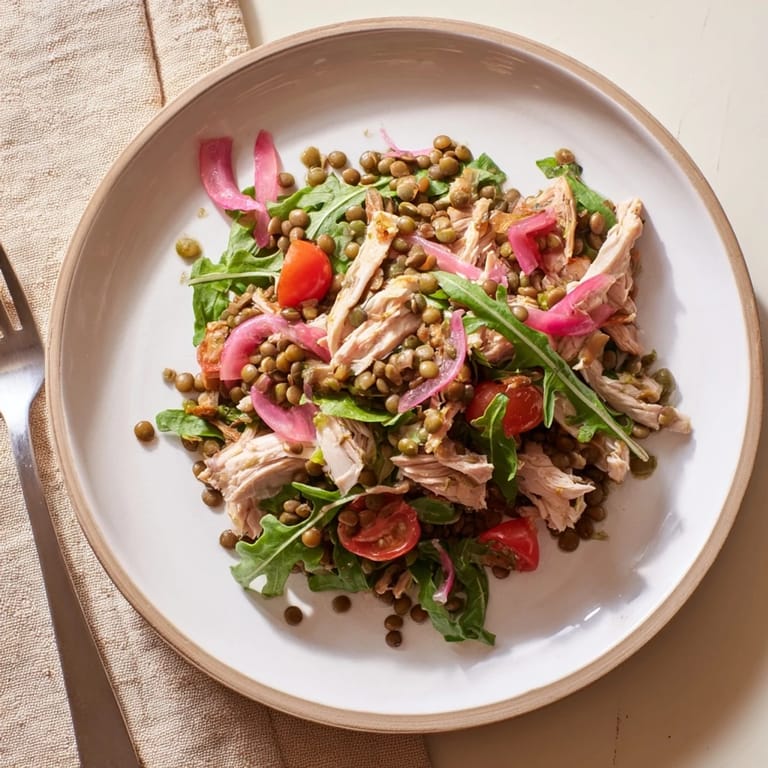 Hearty bowl of the Lentil & Chicken Spring Salad, showcasing protein-rich lentils and shredded chicken on a bed of peppery greens.