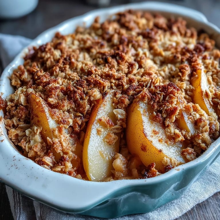 Rustic Pear Crumble with tender pears and a thick, buttery oat topping, served on a wooden kitchen table.