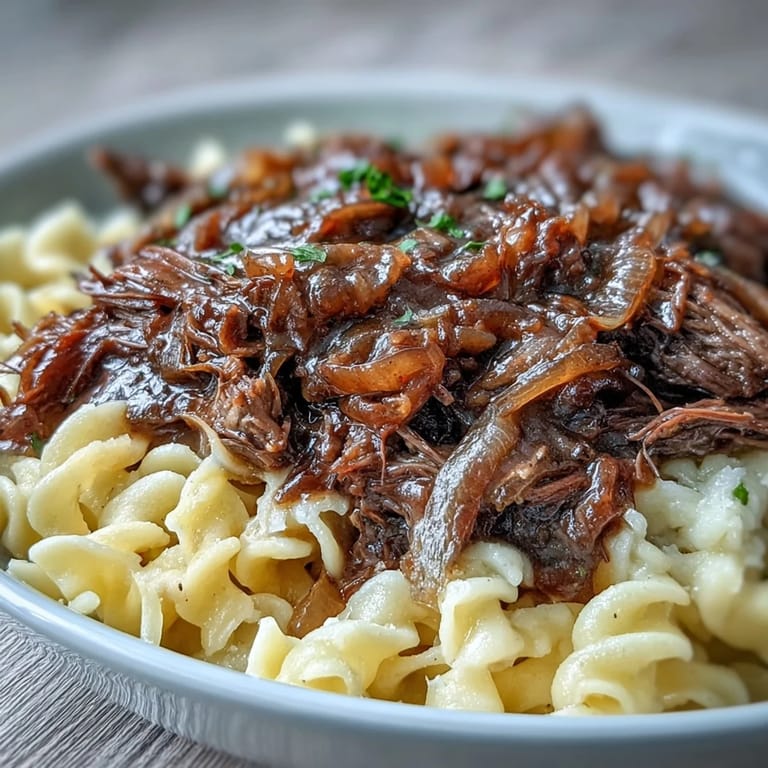 Savory Crockpot French Onion Pot Roast Pasta served family-style, with a side of crusty bread to mop up the rich gravy.